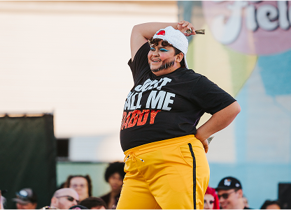 Performer in yellow pants at a pride event radiating happiness and energy