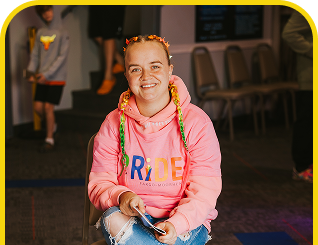 Woman in a pink hoodie, volunteered at a pride event, showcasing her support for LGBTQ+ community.