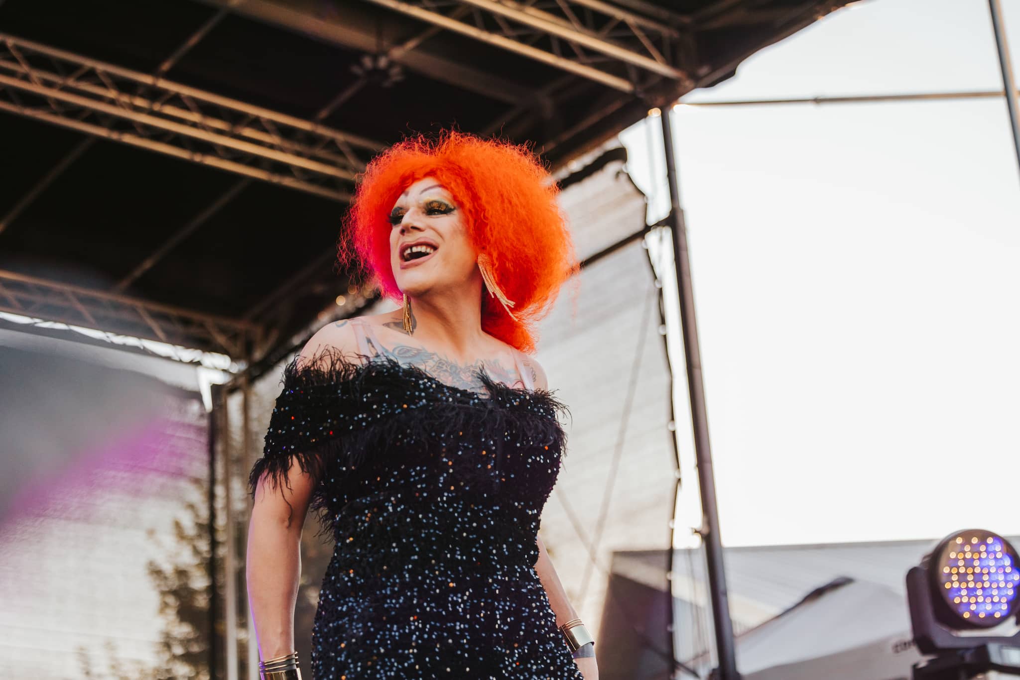 Performer on stage at a lively pride event, showcasing drag and pride culture.